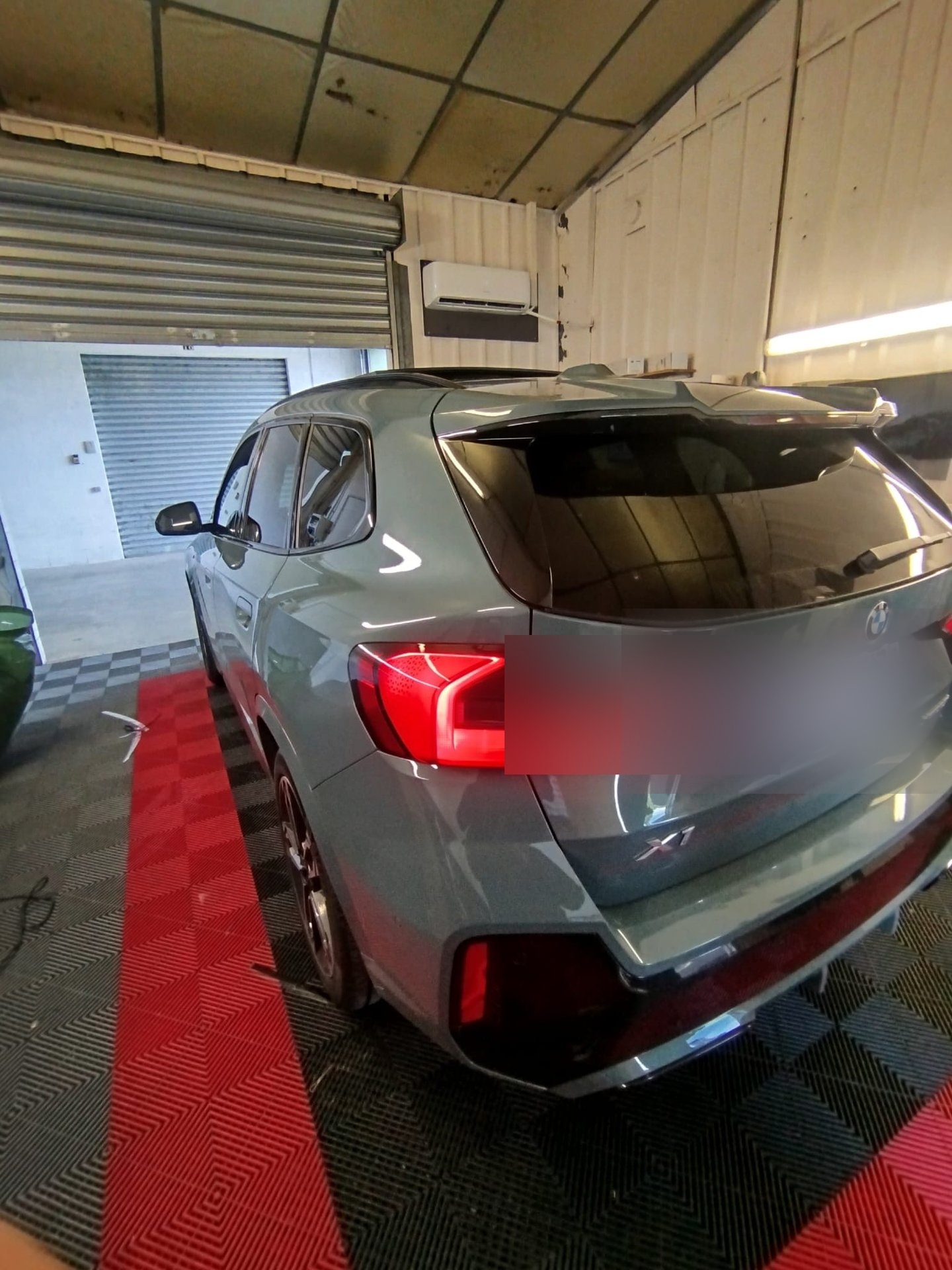 BMW X1 gris Nardo avec vitres teintées, feux arrière allumés